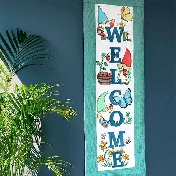 Whimsy & Wildflowers - image features a wallhanging featuring machine embroidery designs making up the world welcome with spring gnomes